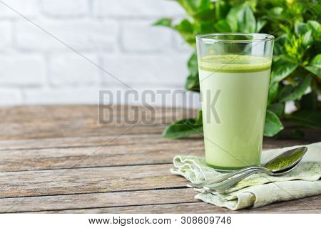 Glass Of Matcha Green Tea Latte On A Wooden Table