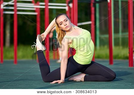 Portrait Of Fit And Sporty Young Woman Doing Stretching In Workout Sports Ground