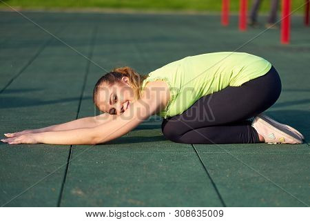 Portrait Of Fit And Sporty Young Woman Doing Stretching In Workout Sports Ground