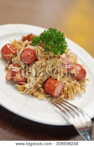 German, Polish, Austrian Cuisine Dish, Bigos - Cabbage Stewed With Meat And Sausages On A White Plat