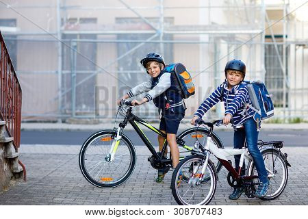 Two School Kid Boys In Safety Helmet Riding With Bike In The City With Backpacks. Happy Children In 