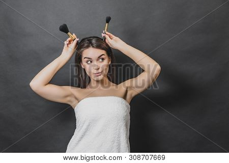 Attractive Girl Wears White Towel. She Is Holding Brushes Near Head. She Is Looking Up And Leftwards