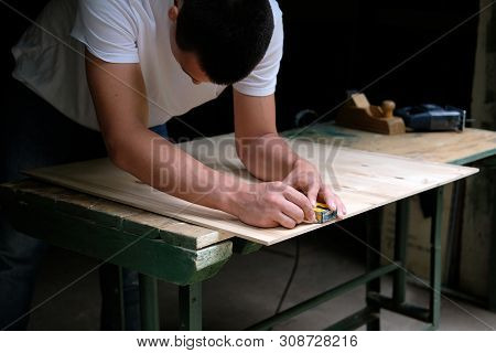 Carpenter Marking Straight Line On Plywood Sheet Using Spirit Level In Carpentry Workshop. Measuring