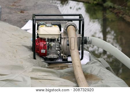 Small Industrial Petrol Water Pump With Strong Black Metal Frame Left On Top Of Improvised Sandbags 