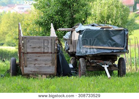 Two Old Rustic Dilapidated Wooden Tractor Trailers With Four And Two Tires Covered With Thick Nylon 
