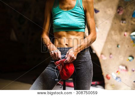 Slender Rock Climber Holds A Bag Of Magnesia. Training On The Climbing Wall. Strong Female Hands. Wo