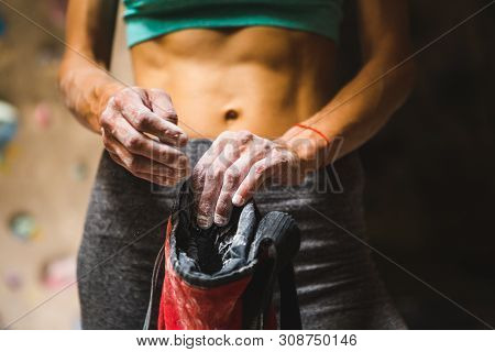 Slender Rock Climber Holds A Bag Of Magnesia. Training On The Climbing Wall. Strong Female Hands. Wo