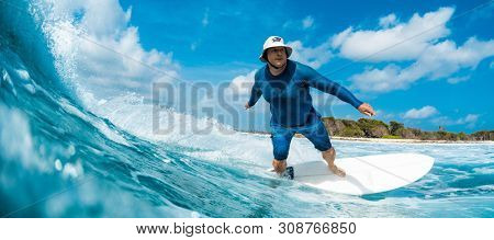 HIMMAFUSHI / MALDIVES - MARCH 08, 2019: Adult man rides the ocean wave on the Sultans surf spot in Maldives