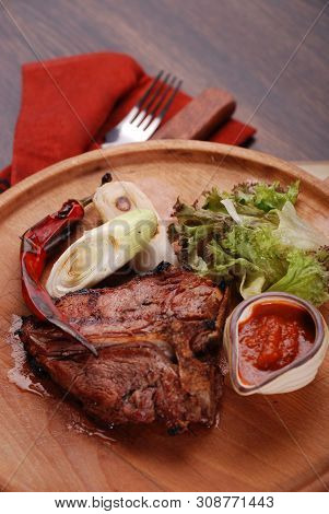 Well-done Steak With Suace And Vagetables. Reastaurant Dishes On The Wooden Table. Food Photo For Re