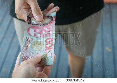 Cropped Shot View Of Someone Give The Money (new Zealand 100$ Dollars) To Each Other.