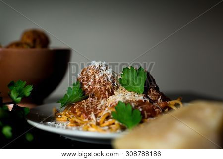 A Close-up Shot Of A Plate Of Rustic Spaghetti And Meatballs With A Bowl Of Meatballs, Parmesean Che