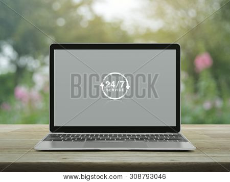 24 Hours Service Icon With Modern Laptop Computer On Wooden Table Over Blur Pink Flower And Tree In 