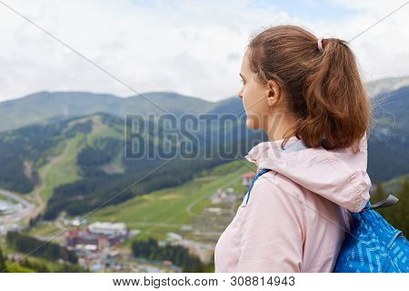 Profile Of Experienced Traveller With Pony Tail Wearing Backpack And Rose Jacket, Enjoying Mountain 