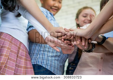 Group Of Children Putting Their Hands Together In Classroom .multiracial. Low Angle