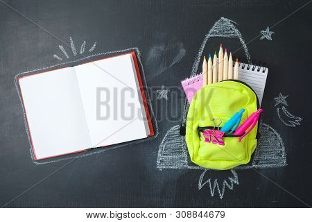 Back To School Concept With Small Bag Backpack, School Supplies And Rocket Sketch Over Chalkboad Bac