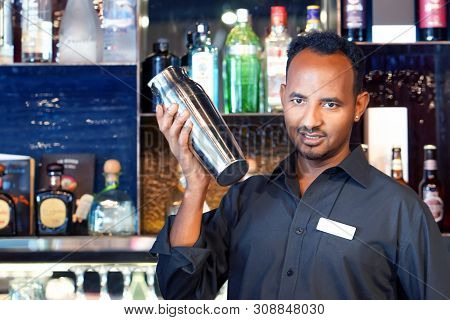 Professional African Bartender Male Holding In Hands A Shaker With A Fresh Delicious Cocktail. Barte