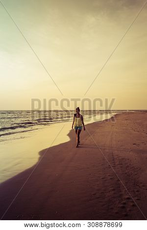 Girl Walking Along The Beach At Sunset