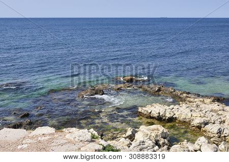 View Of The Sea From The Rocky Shore. Blue-turquoise Water, Open Space And A Vessel In The Road Away