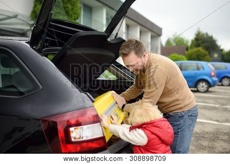 Handsome Man And His Little Son Going To Vacations, Loading Their Suitcase In Car Trunk. Automobile 
