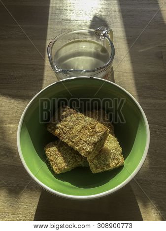 Three Wheat Biscuits In A Breakfast Bowl With A Cup Of Milk On A Table With A Ray Of Sunlight Pourin