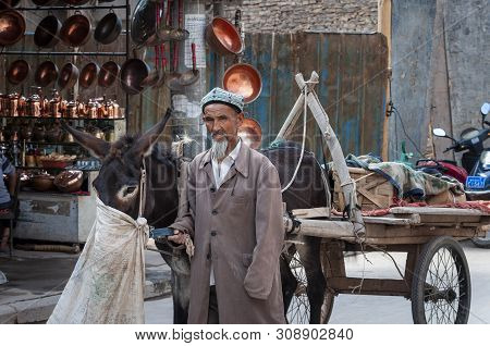 Kashgar, Xinjiang, China - August 14, 2012: Uyghur Man With A Donkey At A Street Market In The City 