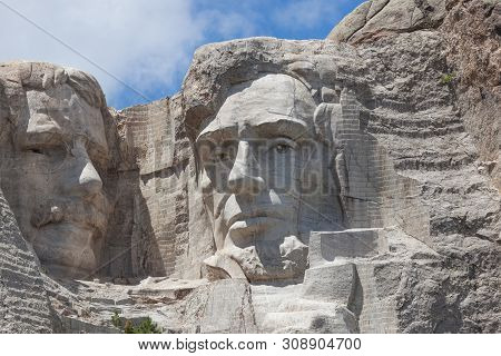 Sunshine, Blue Sky And White Clouds Provide A Striking Back Drop For Two Of The Carved Faces Of Famo