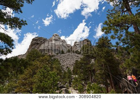 Two Young Girls Walk Up A Stairway Below The Emposing Rock Features Of Four United States Presidents