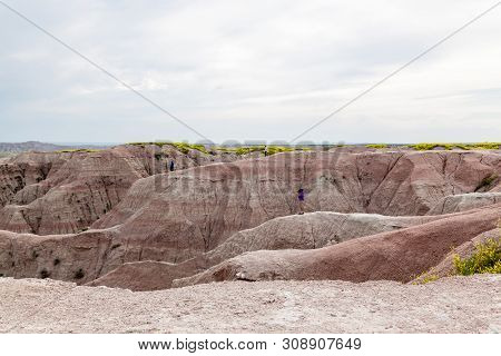 Tourists Stand On Top Of Dramatic Mountain Formations Carved Out By Erosion Showing Layers Of Rocks 