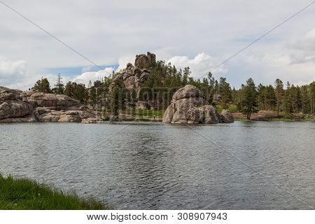Sylvan Lake On A Cloudy Day In South Dakota With Large Granite Rock Formations, Tall Trees And Peopl