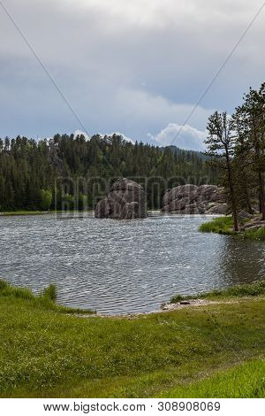 Large Granite Rock Formations And Trees Along The Shoreline Of  Sylvan Lake In South Dakota.