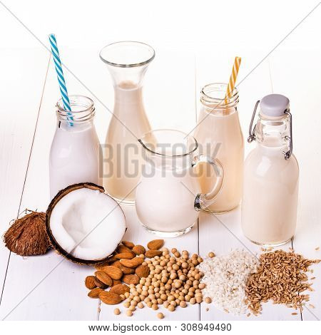 Types Of Vegetable Milk, And Organic, In Glass Containers On The Table In White Wood