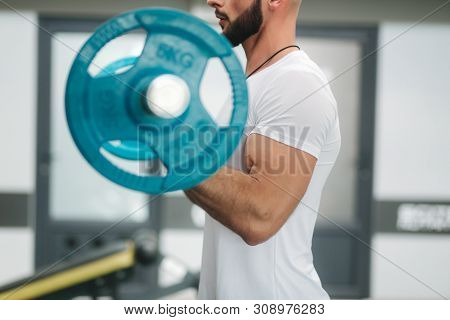 A Young Athlete Trains In The Gym. Trians Biceps Muscules