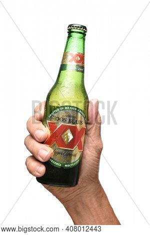 IRVINE, CALIFORNIA - JULY 25, 2019: A hand holding a bottle of Dos Equis Lager over white.