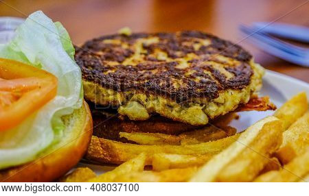Fried Crab Cake Sandwich On Bun With Lettuce And Tomato And French Fries
