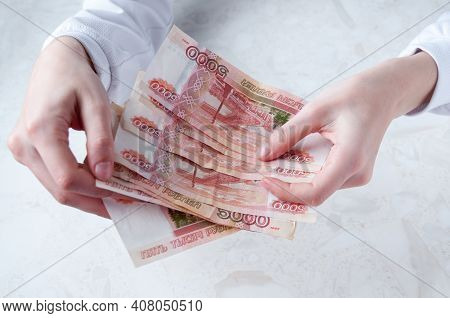 Women's Hands Hold A Bundle Of Large Bills Of Five Thousand Rubles Over The Table