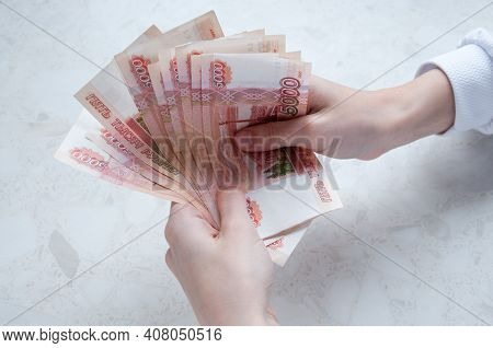 Women's Hands Hold A Bundle Of Large Bills Of Five Thousand Rubles Over The Table