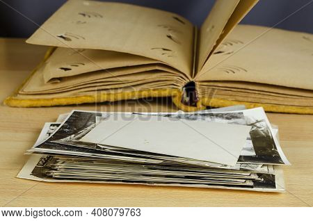 An Open Old Photo Album Wrapped In Yellow Velvet And A Stack Of Black And White Photos In The Foregr