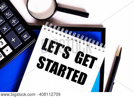 On A Blue Background, Near The Calculator, Magnifying Glass And Pen, A Notebook With The Inscription