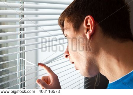 Young Man Is Spying Next To Jalousie In A Room