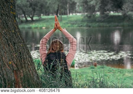 Young Woman Practicing Yoga In The Park. Person In Defocus. Concept Of Mental Health, Wellness And R