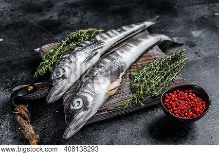 Raw Icefish On A Wooden Cutting Board. Black Background. Top View