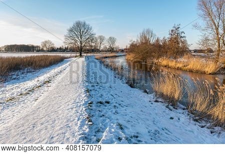 Snowy Path In A Dutch Polder Landscape On A Sunny Day In The Winter Season. The Photo Was Taken In T
