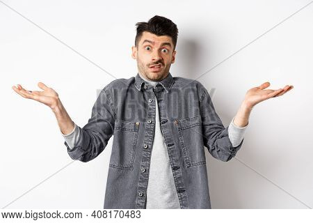 I Dont Know. Clueless Young Man Shrugging And Looking Confused, Have Nothing To Say, Standing Unawar