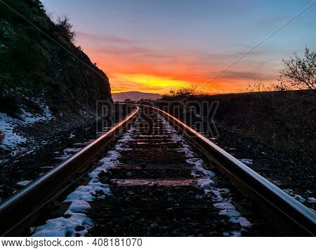 Sunset Over Railroad Reflecting On The Rails Disapearing Around A Curve