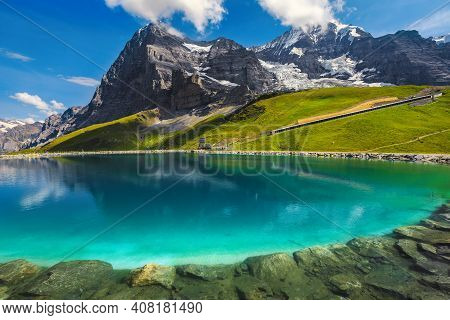Majestic Clean Blue Lake With The High Eiger Mountain. Snowy Mountains With Glaciers And Fallbodense
