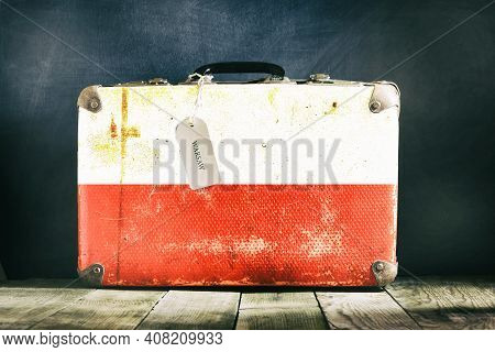 Old Suitcase With The Poland Flag On Wooden Background. Travels