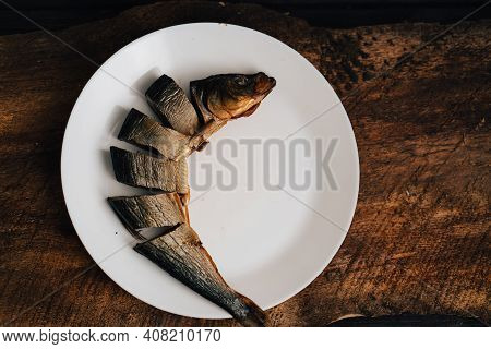 Sliced Dried Fish On A White Plate On A Wooden Table