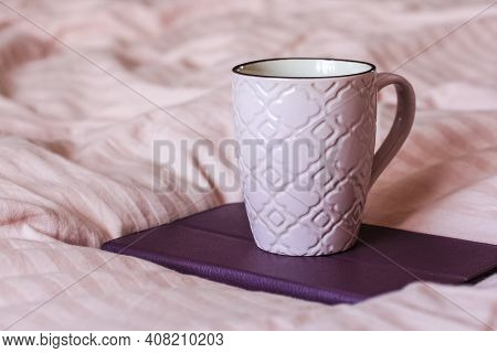 A Pink Cup Of Tea Sits On The Pink Blanket In The Bed.home Atmopshere.