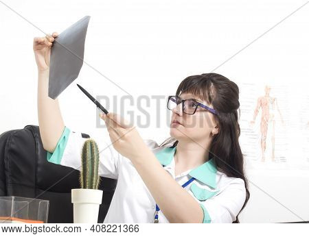 Female Doctor Pulmonologist Deciphers X-ray Picture Of Lungs With Pneumonia, Background.