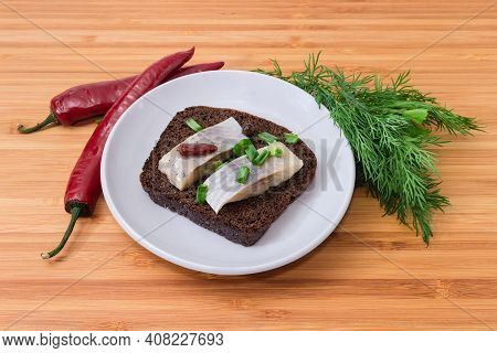 Open Sandwich Made Of Brown Bread, Slices Of Pickled Atlantic Herring Fillet And Chopped Green Onion